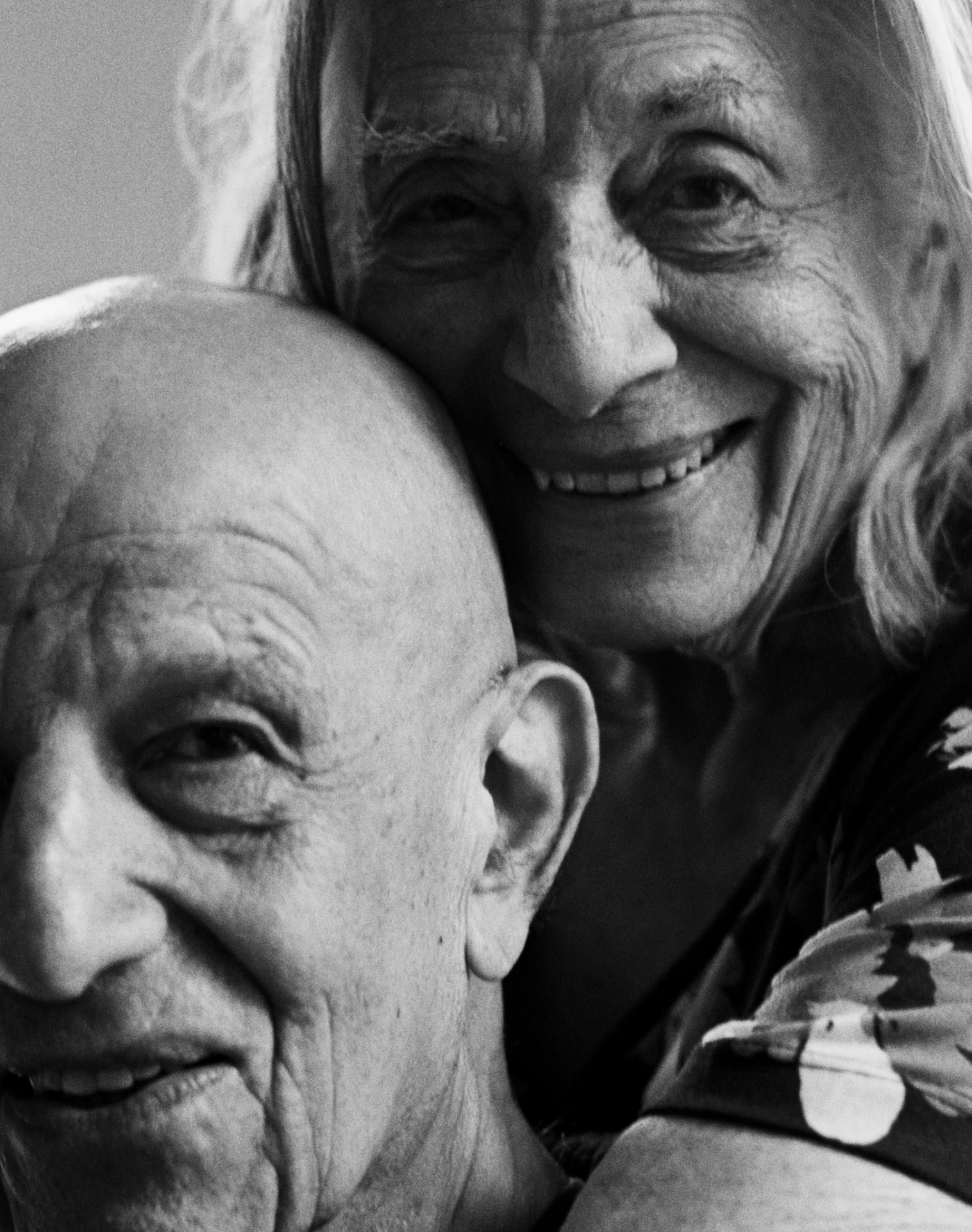 An older couple holding each other close, both smiling